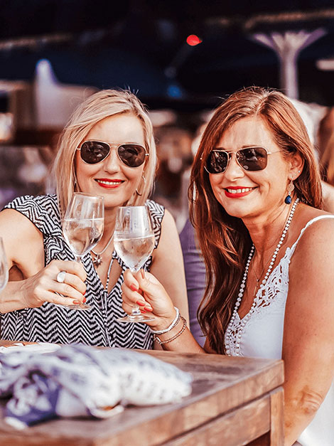 Zwei Frauen stoßen mit einem Glas Wein in der Hand an den Kasematten in Düsseldorf an.