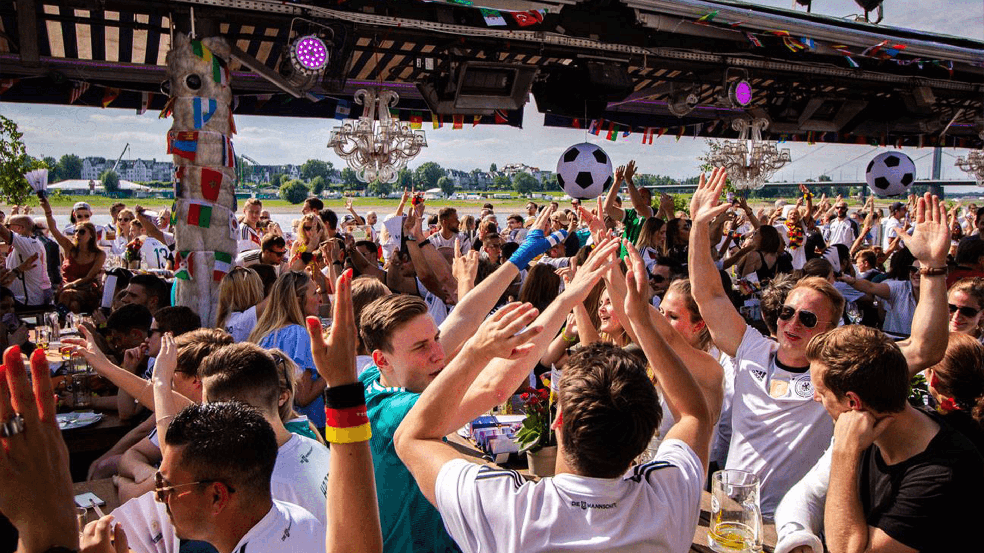 Eine ausgelassene Menschenmenge feiert an den Kasematten in Düsseldorf die Weltmeisterschaft und jubelt über ein Tor.